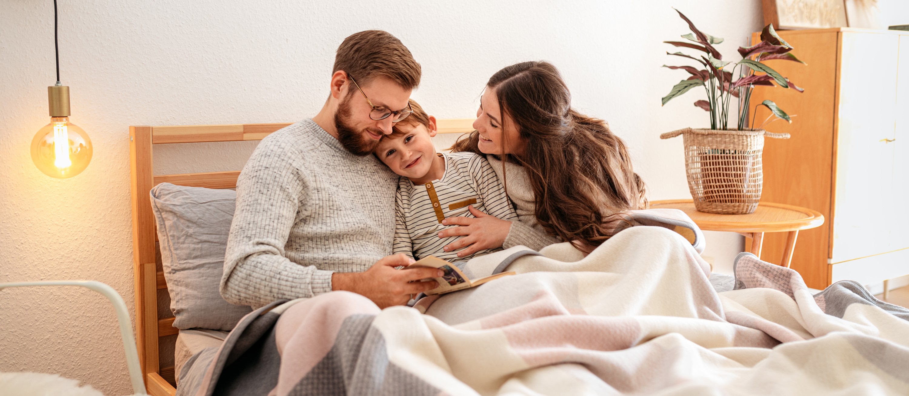 Familie kuschelt mit Biederlack Decke Emotionales Bild: Familie kuschelt im Bett mit Biederlack Kuscheldecke