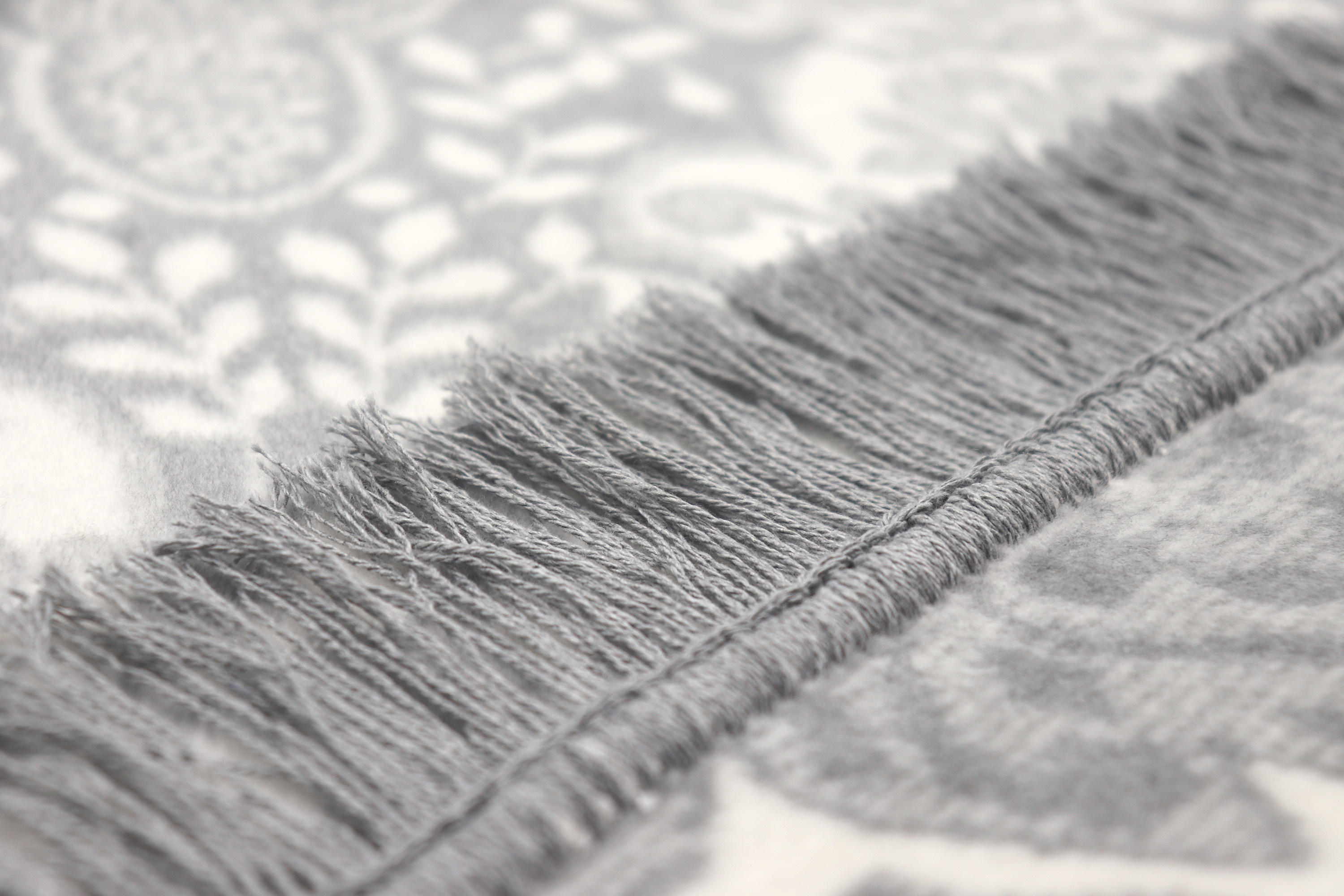 graue Wohndecke "Lace" mit Fransen und Ornament-Design - Detailaufnahme Fransen