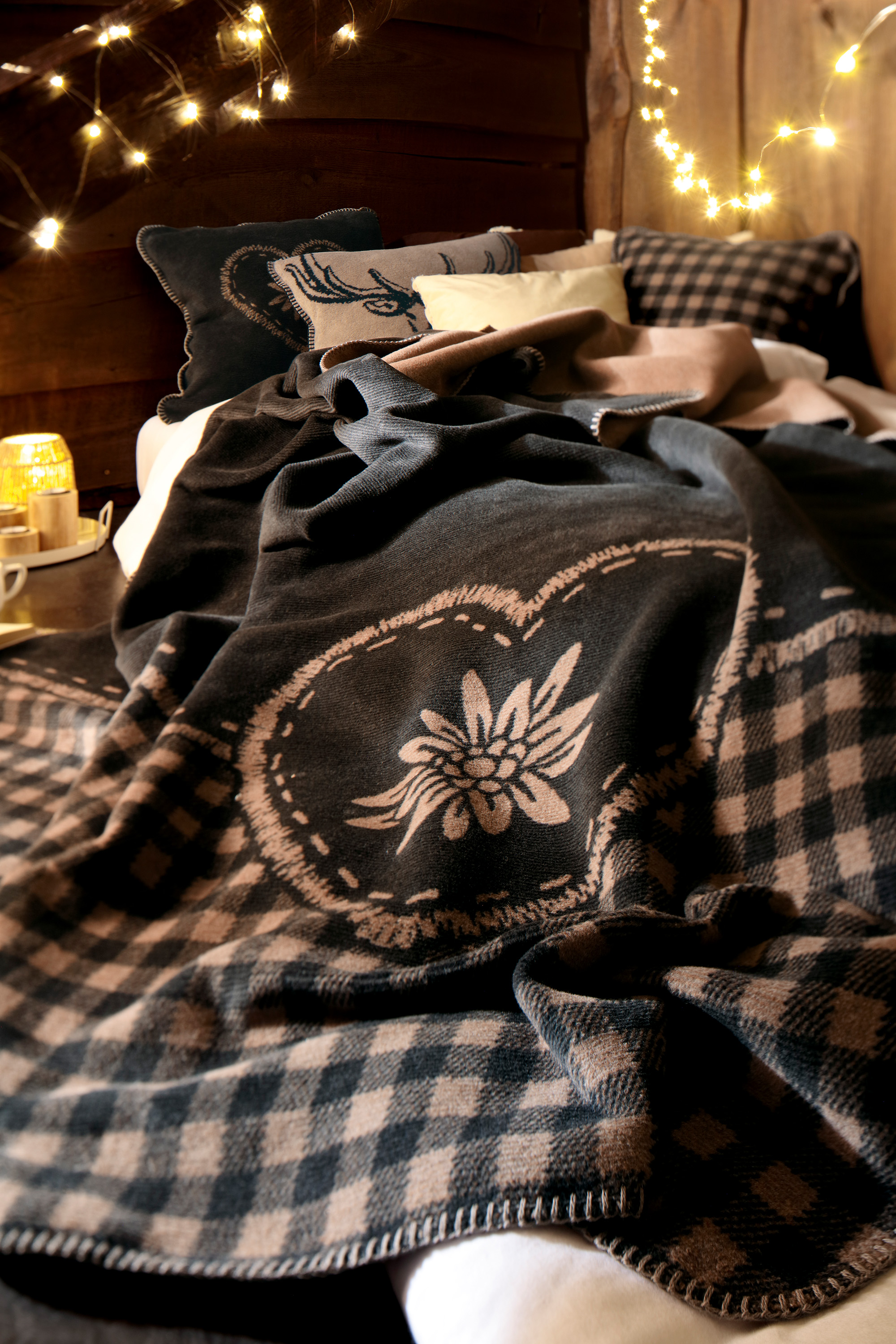 Wohndecke Alp Charm mit passenden Kissen im Hintergrund