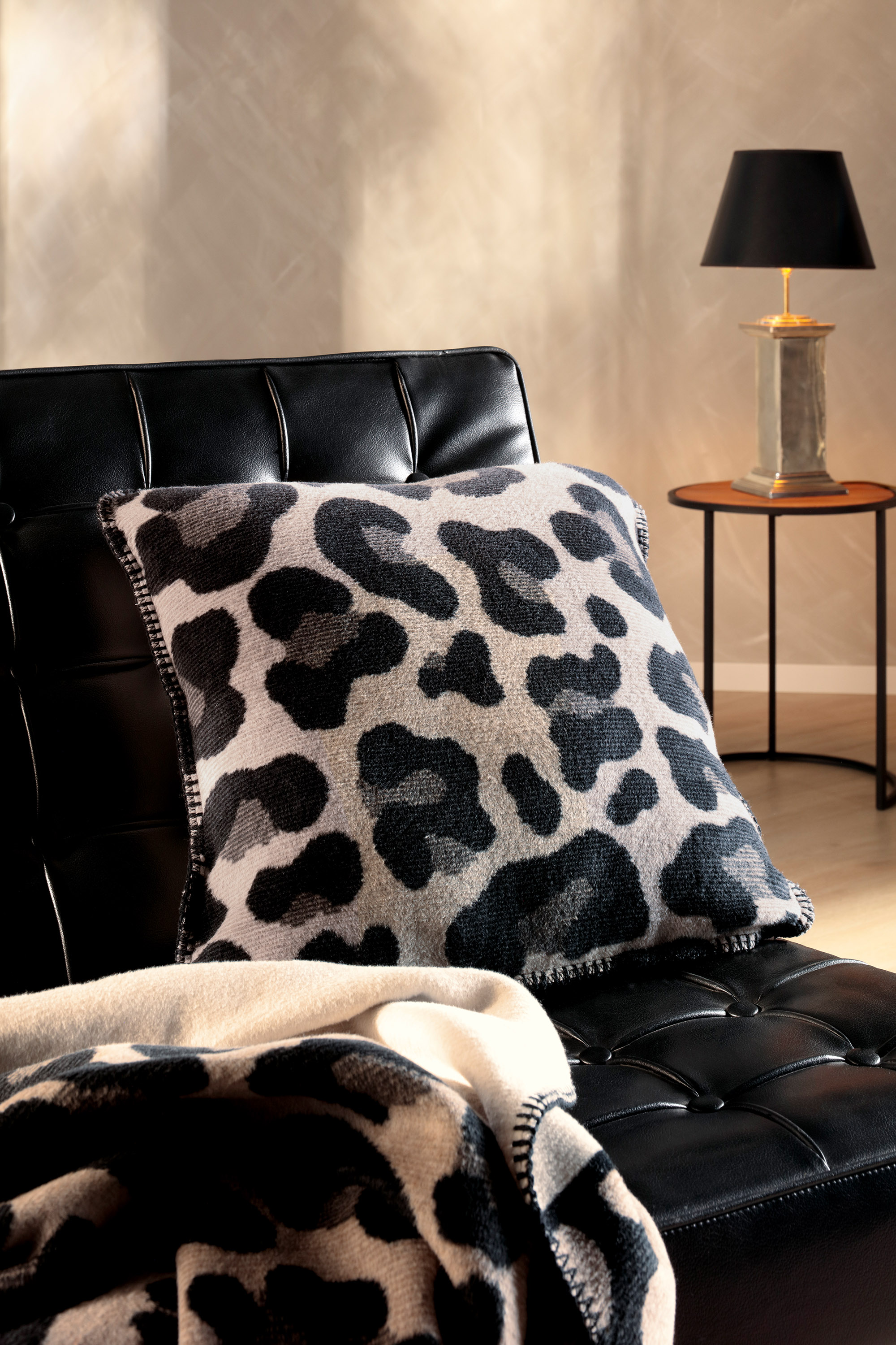 Kissen Leo Part auf Sofa mit Decke im Vordergrund